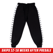 Black track pants with white side stripes featuring repeating killer whale silhouettes and a back pocket.